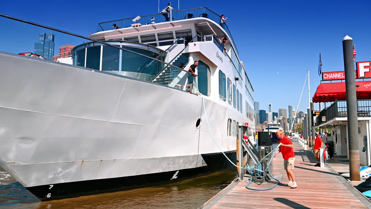 New Jersey, USA, 19 August 2025: Man standing on the board of the cruise boat. Crew member throws the rope to a man standing on the berth