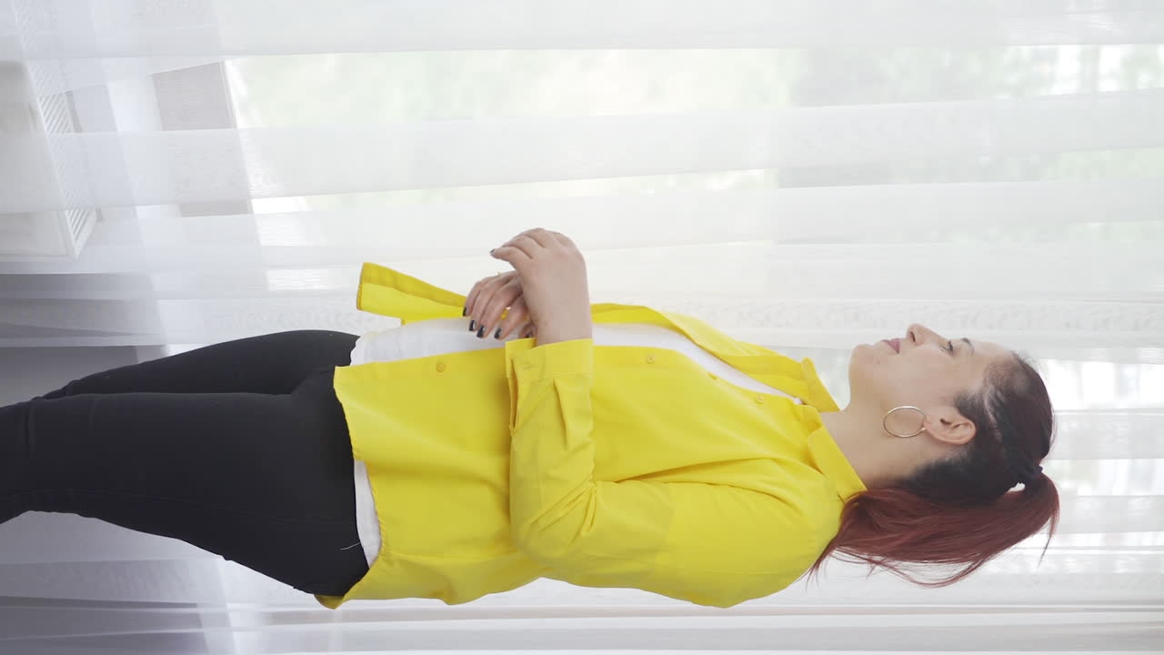 창문 밖을 바라보는 여자의 수직 비디오.