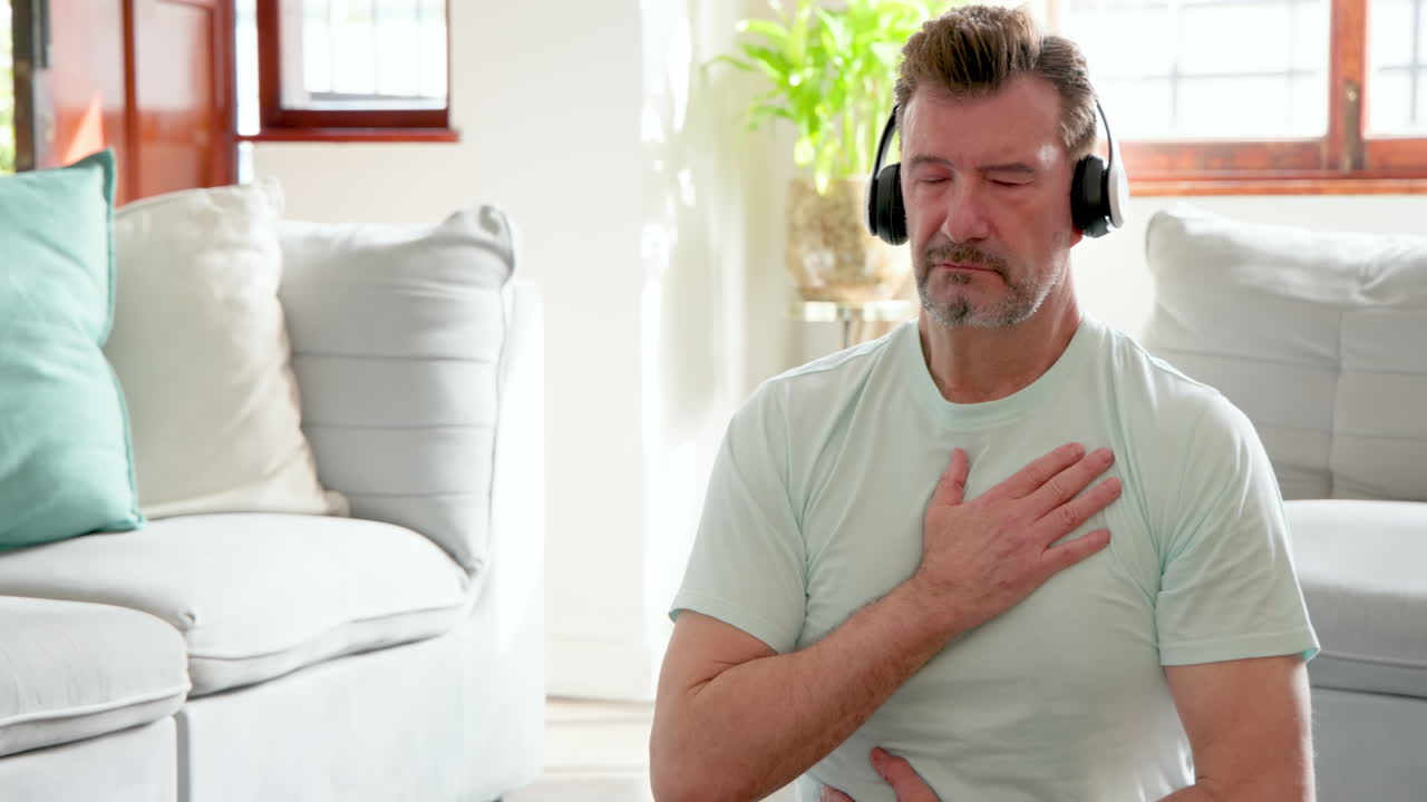Senior man meditating at home with headphones, finding peace and relaxation