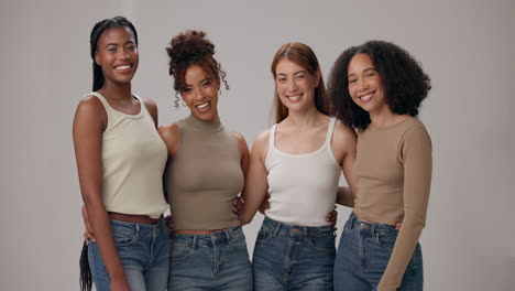 four diverse young women pose for a photo together, smiling and looking happy.