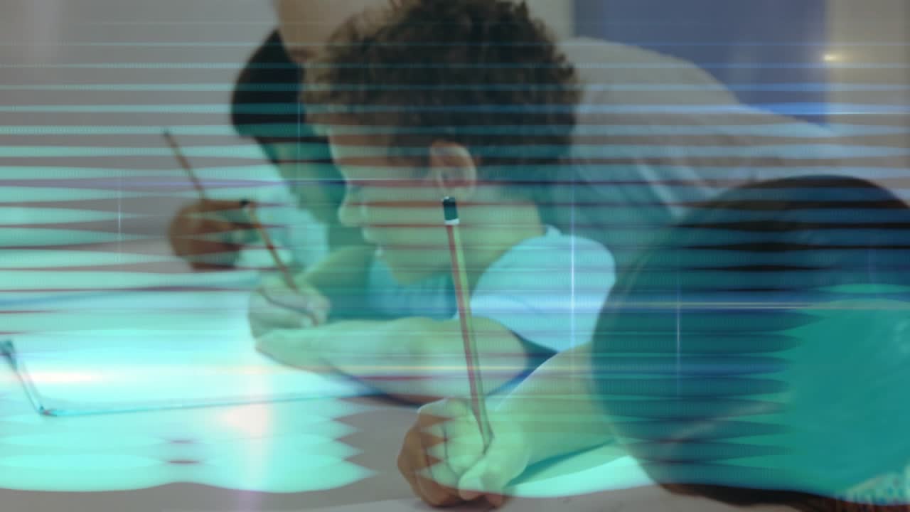 Girl writing with red-striped pencil at desk while teacher leaning over offering education feedback