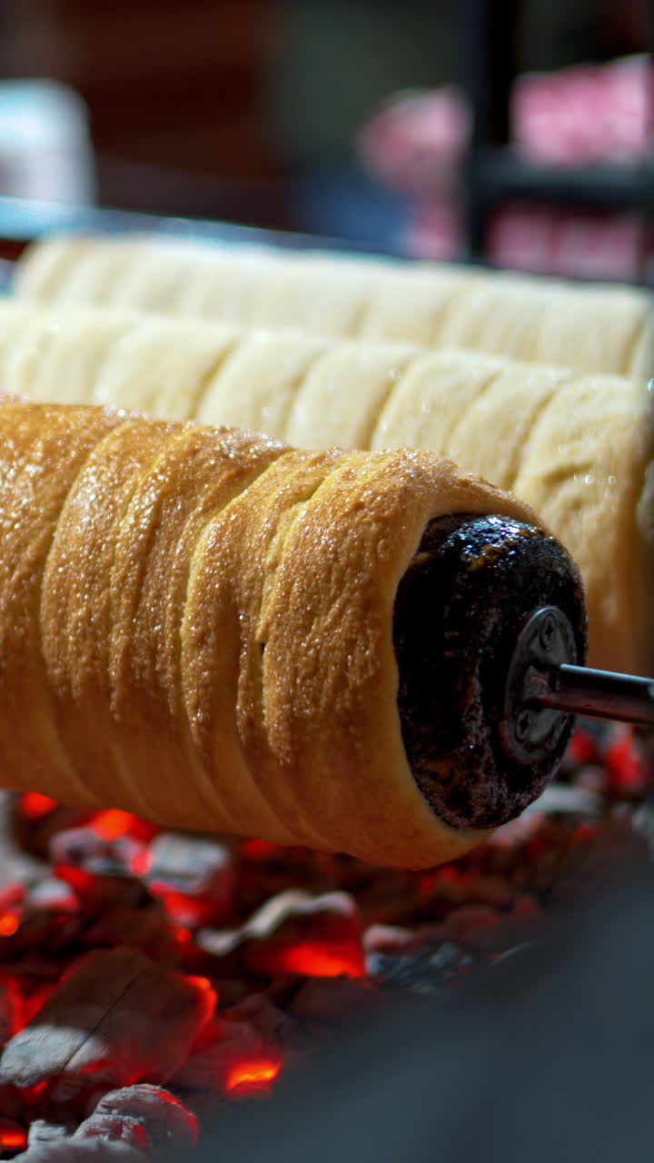 Close up of chimney cakes spinning on smoldering coal. Vertical