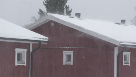 heavy snowfall on traditional red swedish house, establishing, medium