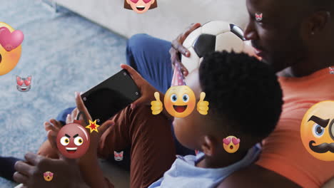 animación de emoticones sobre padre e hijo afroamericanos usando teléfono inteligente con espacio de copia