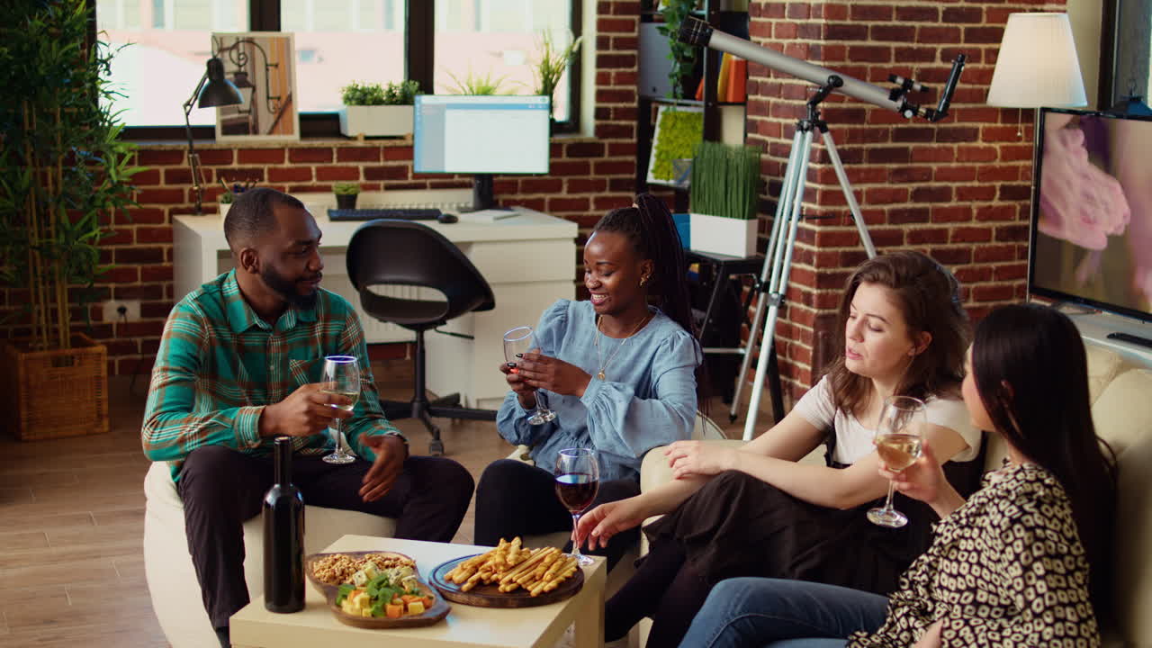 BIPOC friends having entertaining conversation, eating bread sticks from charcuterie board at home