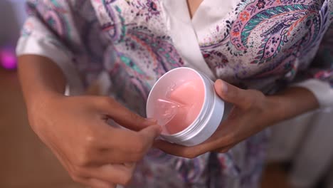 mujer aplicando una máscara facial rosa