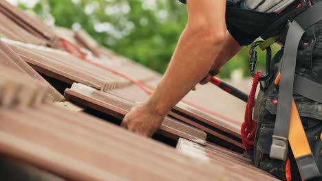 Roofer-installing-clay-tiles-on-top-of-private-estate-roof,-side-view