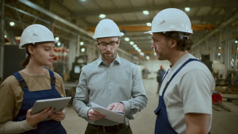 engineer and factory technicians discussing plans in industrial facility