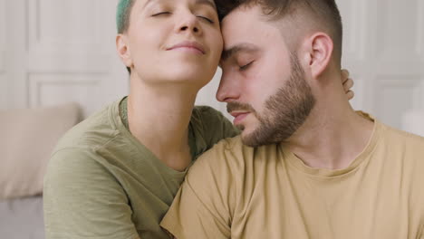 portrait of a loving couple cuddling sitting on the bed at home 1