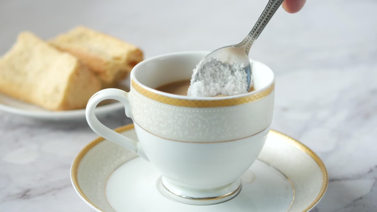 vertiendo azúcar blanca en una taza de té ,