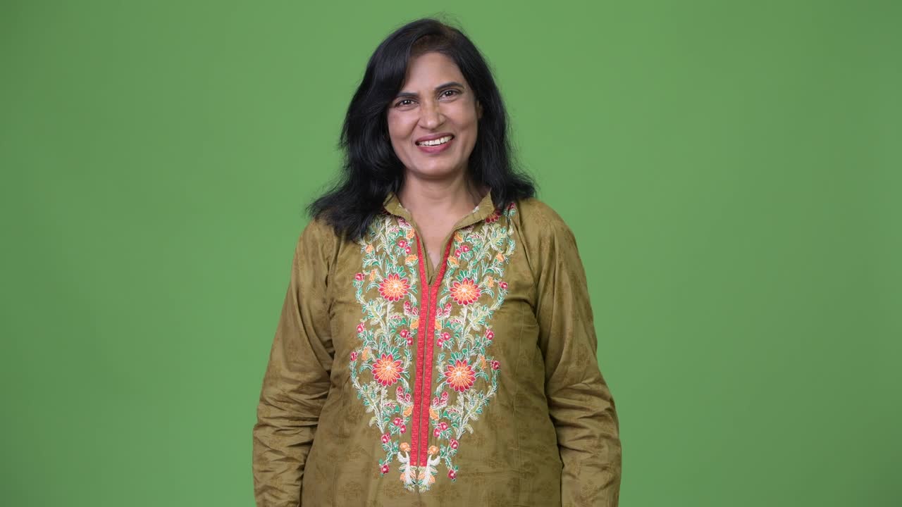 зрелая счастливая красивая индийская женщина улыбается и носит традиционную одежду на зеленом фоне