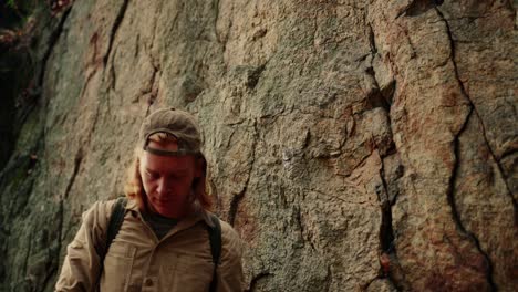 excited hiker with long blond hair rising his phone for selfie, rocky background, vogelberg