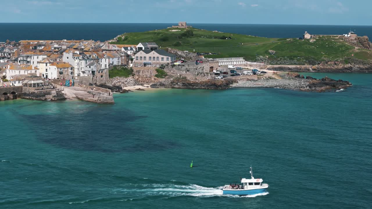 Drone tracking boat right along sea, coastal town in background
