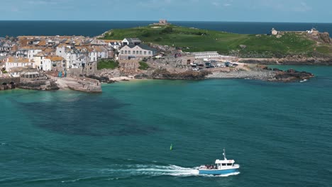 drone tracking boat right along sea, coastal town in background