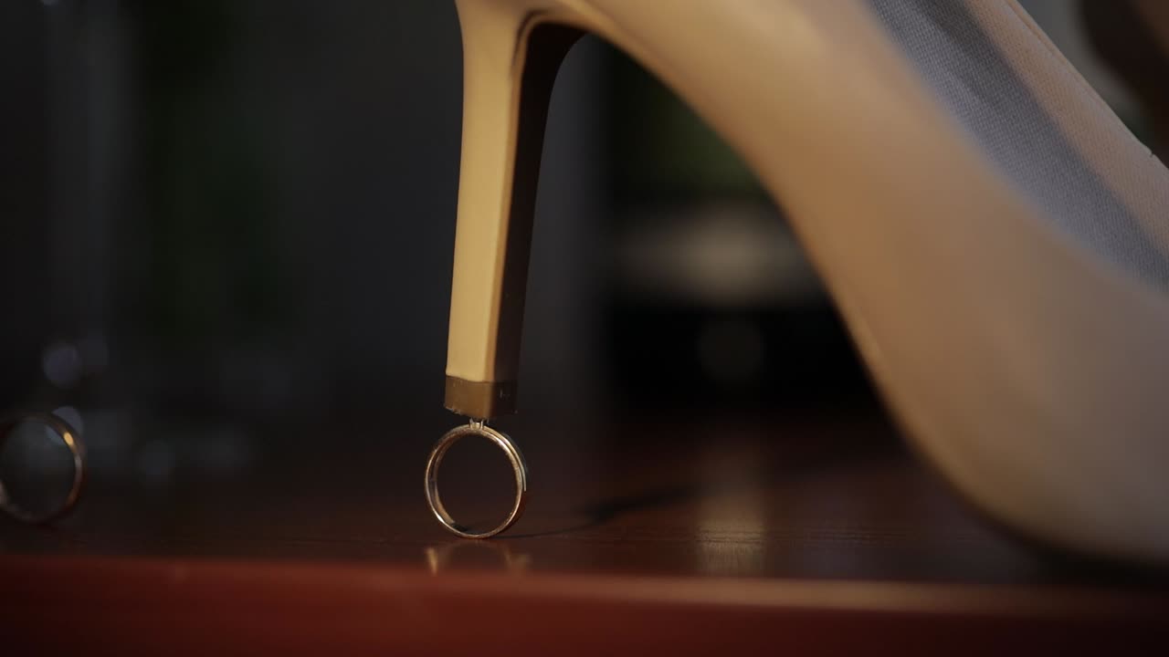 두 개의 웨딩 골드 링이 신부의 웨딩 신발 발 뒤꿈치 근처에 함께 굴러서 약혼 반지와 함께