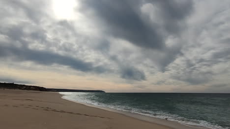 Vista-Frontal-De-Pov-A-Lo-Largo-De-Una-Larga-Playa-Vacía-Sin-Gente-Durante-La-Pandemia-De-Covid-19-Y-Nubes-Oscuras-Arriba