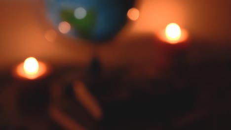 out-of-focus-globe-in-flickering-candles-light-background-on-a-wooden-surface-with-stones-and-ancient-books