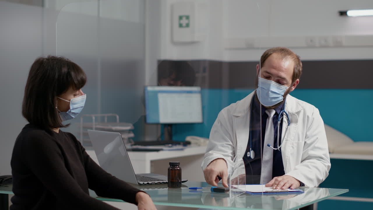 Doctor taking notes and giving prescription paper to female patient