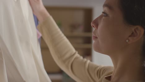 close up of woman at home choosing business suit from clothes rail for job interview 4