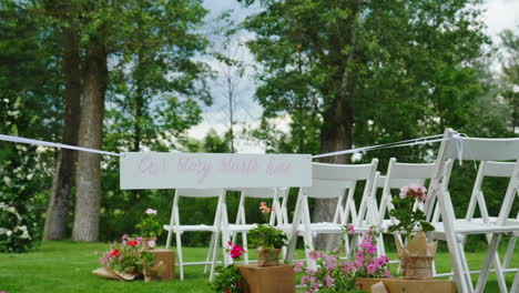 green lawn with rows of white wooden chairs place for the wedding ceremony