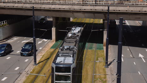 Slowmotion-shot-of-a-tram-travelling-under-an-underpass-with-cars-driving-beside,-Rotterdam