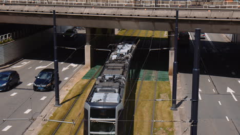 slowmotion shot of a tram travelling under an underpass with cars driving beside, rotterdam