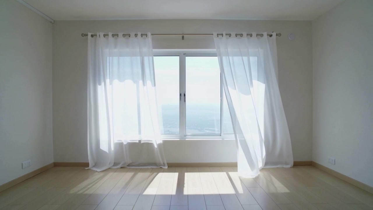 Billowing sheer curtains in empty room, gentle draft pushing panels across window, light shifting