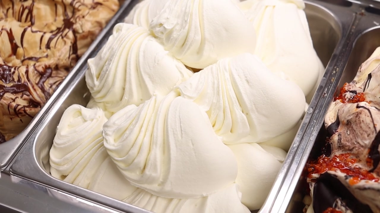 Primo piano di gelato cremoso alla vaniglia in vaschetta espositiva di metallo