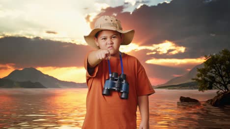 niño asiático con un sombrero y binoculares apuntando con el dedo hacia ti y hablando furiosamente en contra de culparte en un lago. niño investigador, concepto de aventura de turismo de viaje