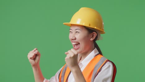 close up of side view of asian female engineer with safety helmet screaming goal celebrating working in the green screen background studio