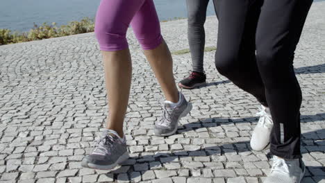 legs of active retired joggers running on promenade