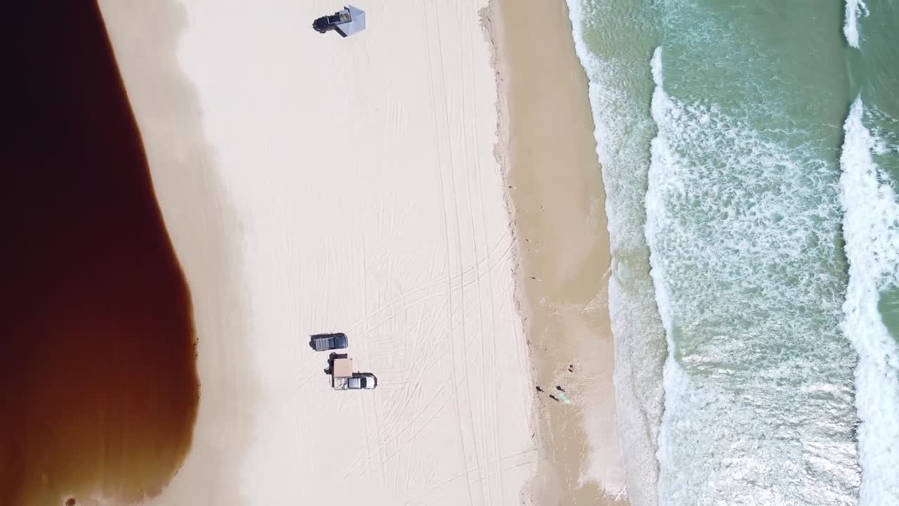 дрон сверху вниз пана над песчаным пляжем с автомобилями кемпинг на острове страдброк, австралия, чистые волны воды и спокойные пейзажи океана