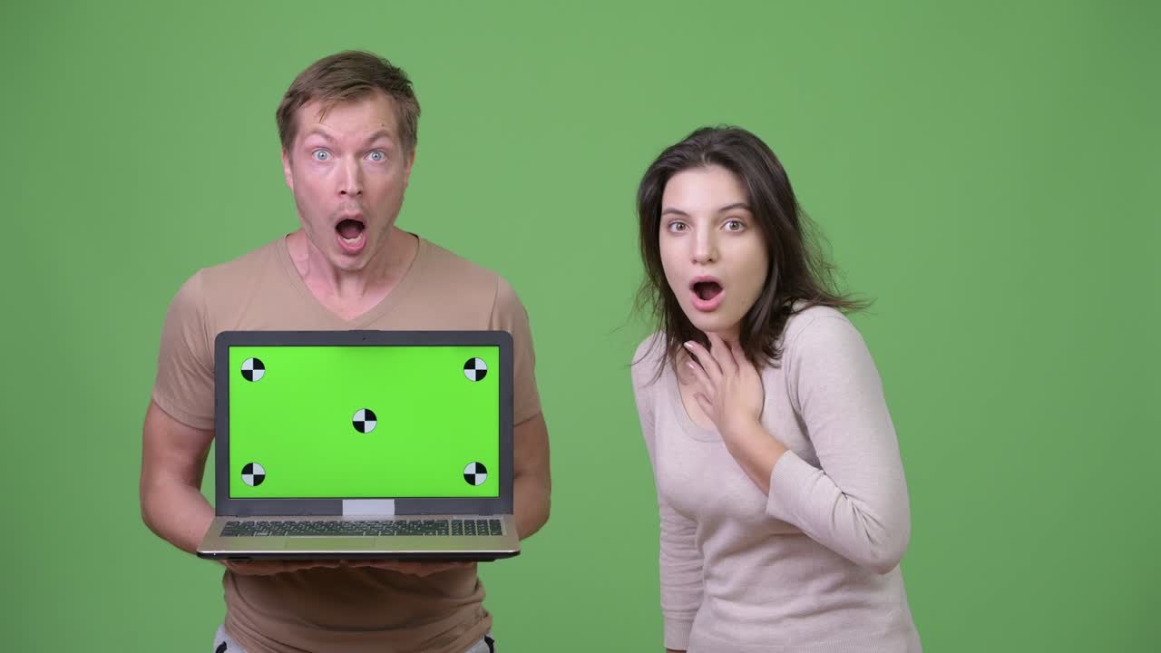 Young couple showing laptop while looking shocked together