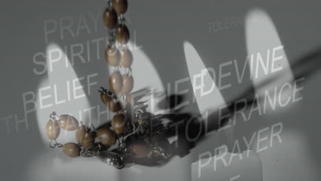 multiple religious words against burning candle and christian rosary falling