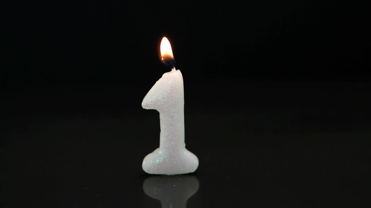 Abstract red decorative shapes over number one birthday burning candle against black background