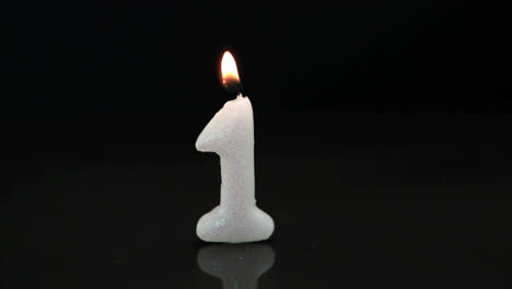 abstract red decorative shapes over number one birthday burning candle against black background