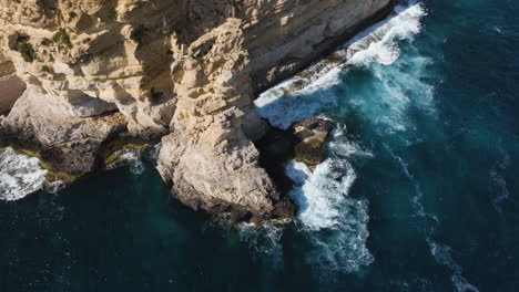 Vista-Aérea-Inclinada-Alrededor-De-Acantilados-Rocosos-En-La-Costa-De-La-Soleada-Isla-De-Malta