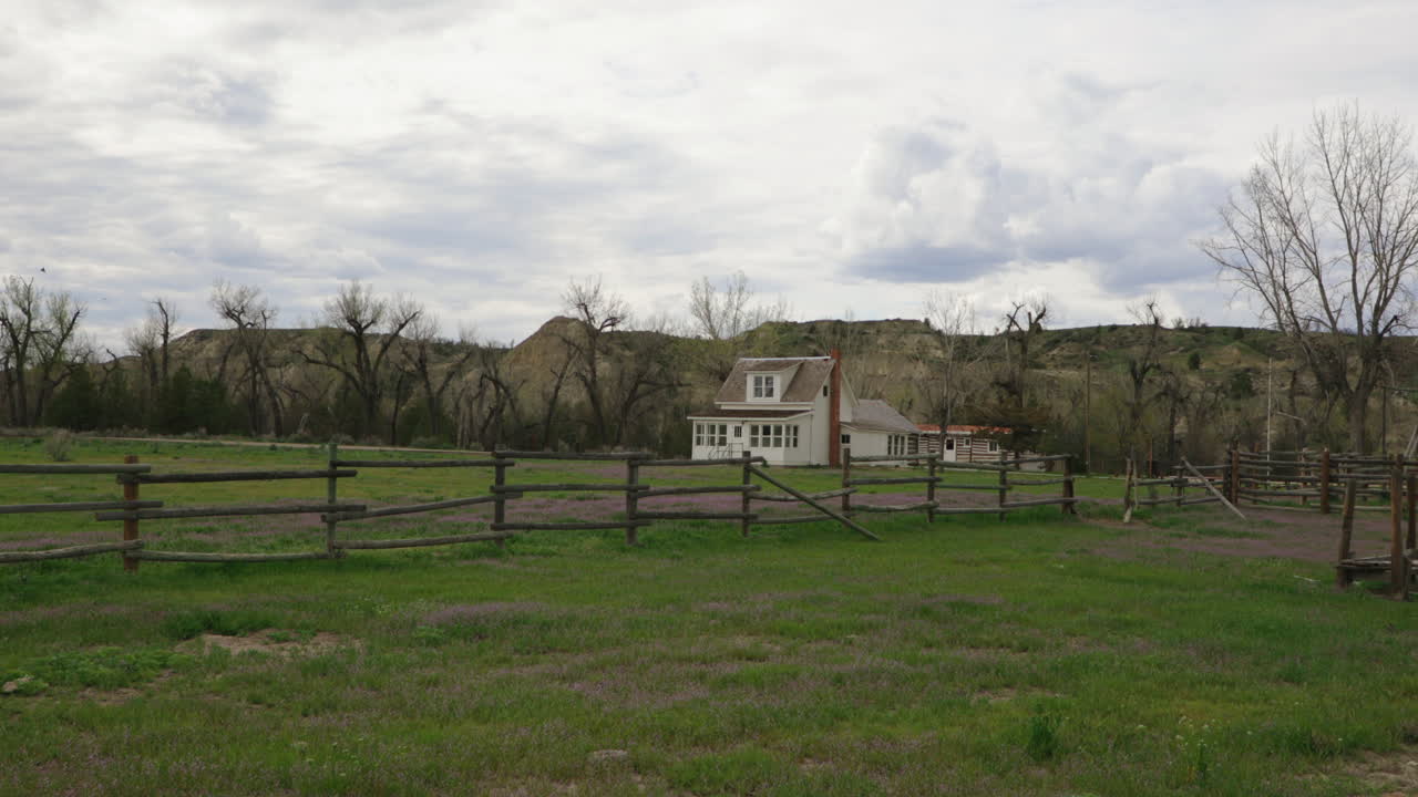 Ranch House on the prairie with wooden fence and cloudy sky