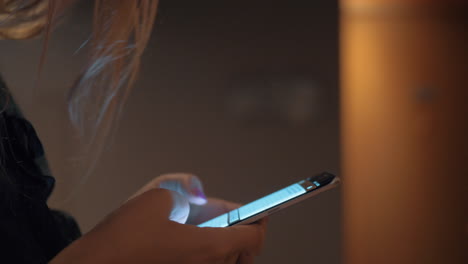 woman typing message on cell when walking in the hallway of hotel