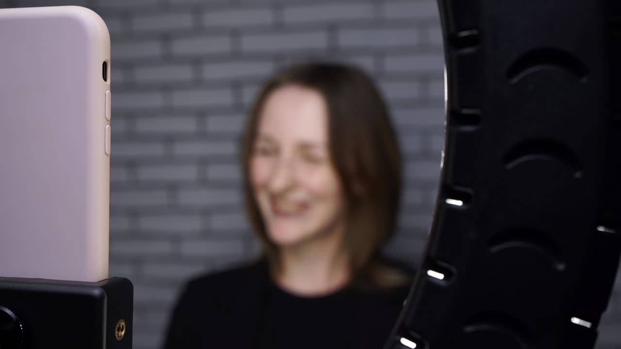 블로거 여성이 벽돌 벽 배경에 링 램프를 고 촬영한 비디오