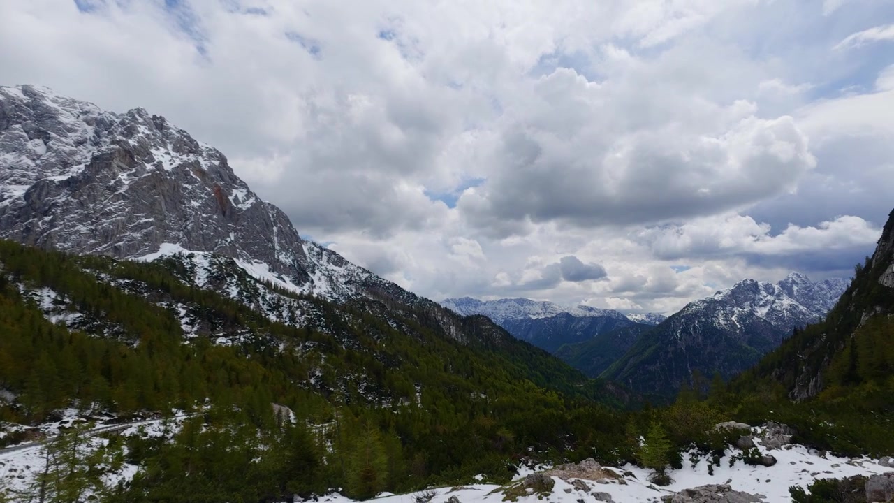 Slovenya'daki Vrsic Geçidi'nde karlı zirvelere sahip ilkbahar manzarası, fon oluşturuyor.