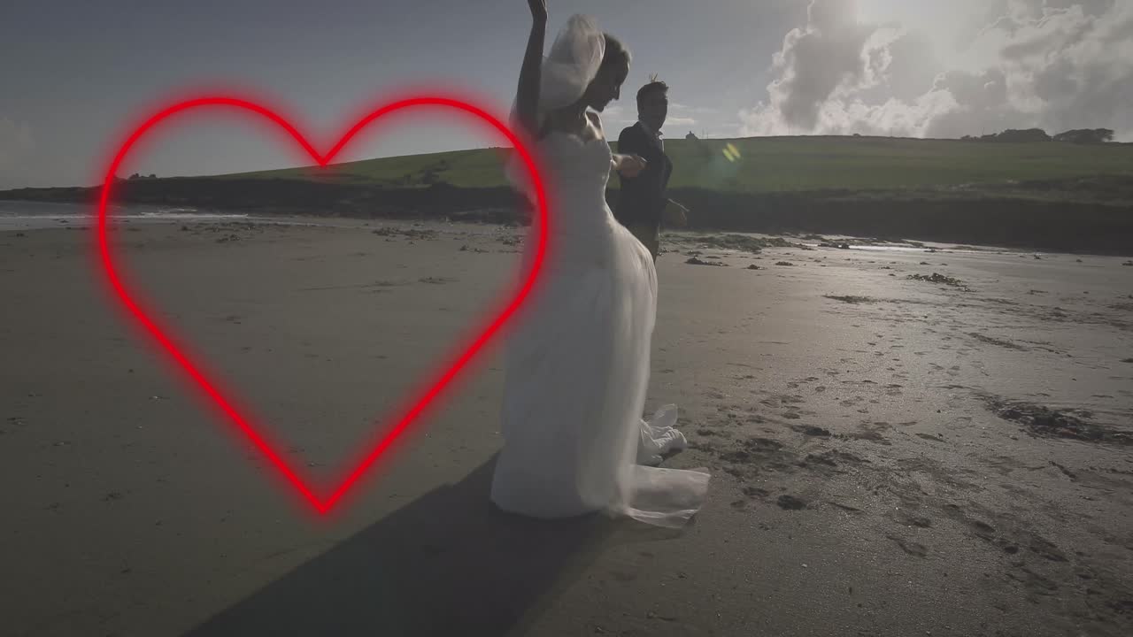 анимация неонового сердца над кавказской супружеской парой, танцующей на пляже