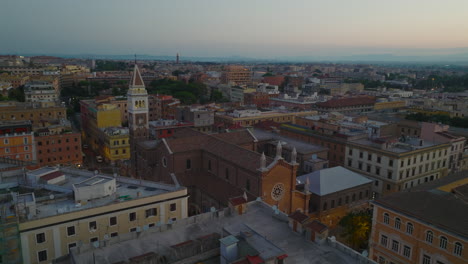 Aerial-view-of-historic-church-and-square-tower-among-town-development-in-city-at-twilight.-Rome,-Italy