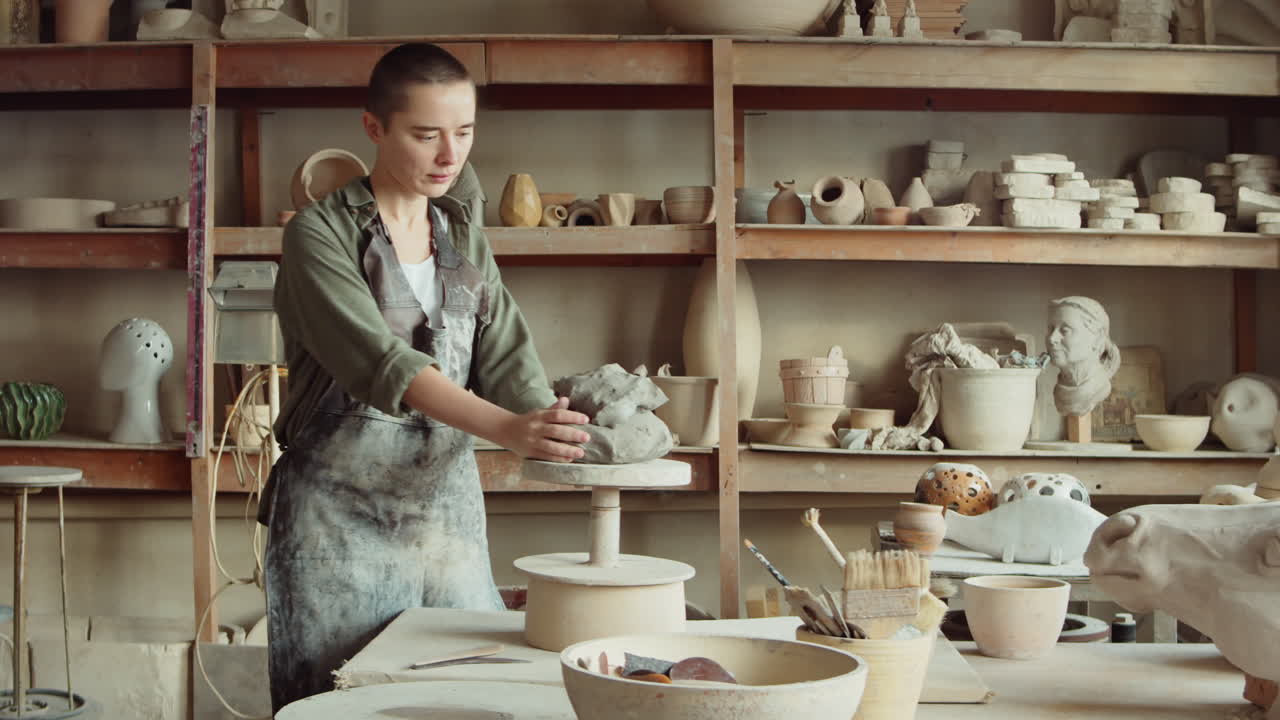 여자 조각가 가 일 을 위해 점토 를 준비 하고 있다