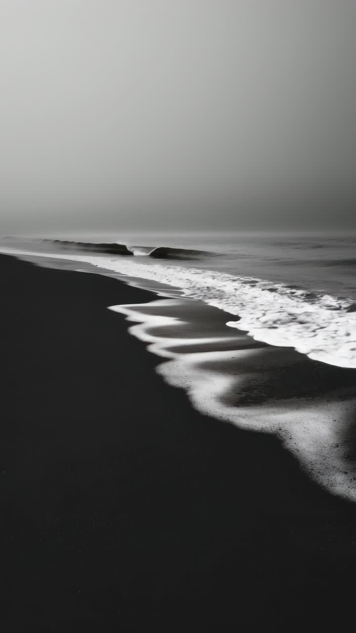 Vista aérea de uma praia de areia preta com ondas brancas, criando um contraste marcante