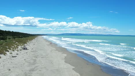 Aerial-hover-above-Woodend-Beach-in-summertime-with-beautiful-rolling-waves-and-turquoise-colored-ocean