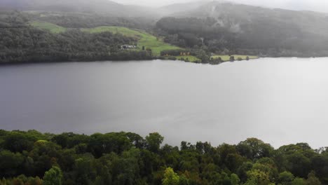 Aerial-View-Of-Calm-Loch-Tummel-Surface-With-Rolling-Mist-Seen-In-Background-Over-Valley-Hills