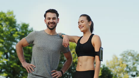 joven pareja de corredores posando al aire libre y sonriendo a la cámara