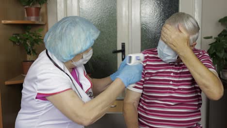 nurse measures temperature with non-contact electronic thermometer of sick grandfather. coronavirus