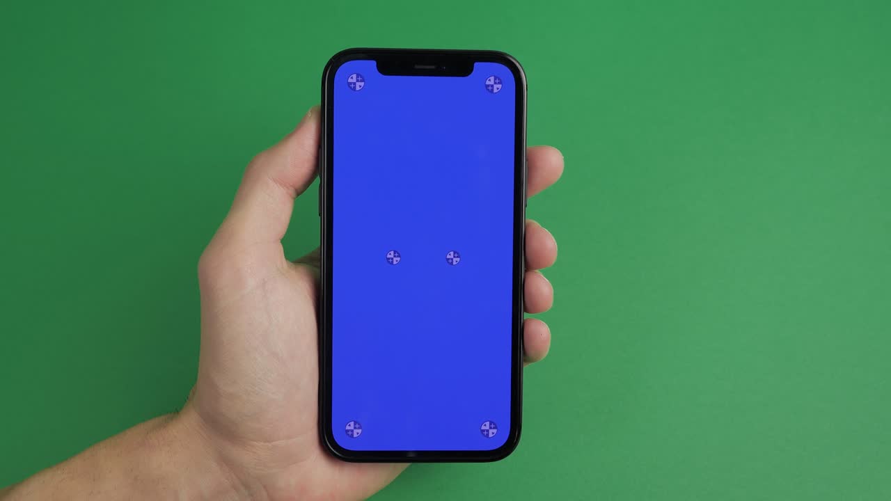 primer plano de mano masculina sosteniendo teléfono móvil con pantalla azul vertical clave de croma tecnología de teléfono inteligente teléfono celular pantalla de mensaje táctil mano en fondo de pantalla verde.